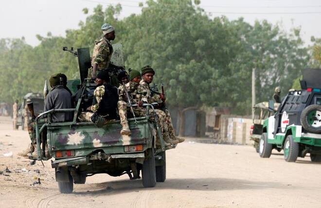Nigerian military ride on their truck as they secure the area where a man was killed by suspected militants during an attack around Polo area of Maiduguri