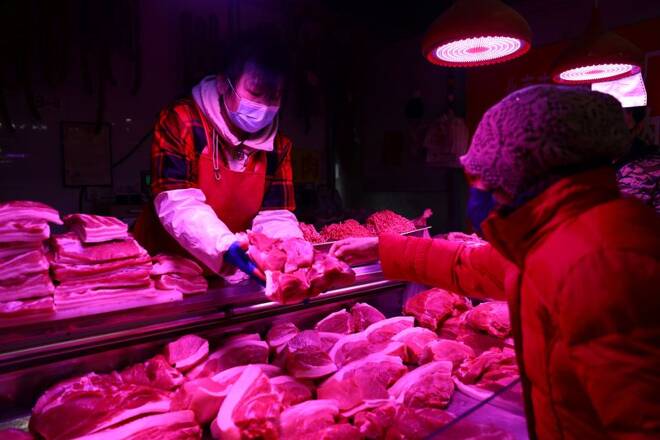 A customer buys pork at a meat stall inside a morning market in Beijing