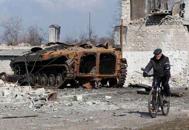 A local resident rides a bicycle past a charred armoured vehicle in Volnovakha