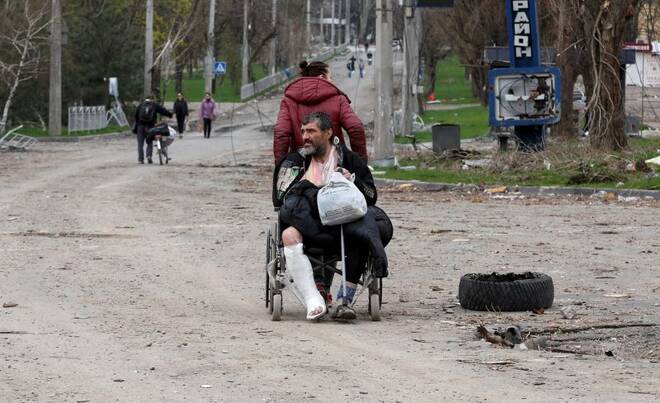 A woman transports an injured man in Mariupol