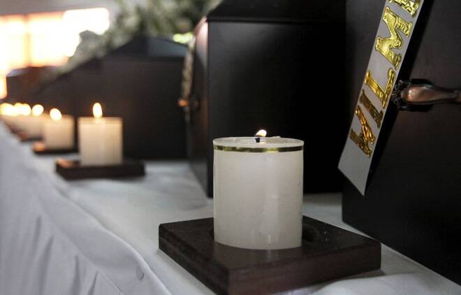 Lit candles are seen in front of coffins containing human remains during a ceremony in Medellin