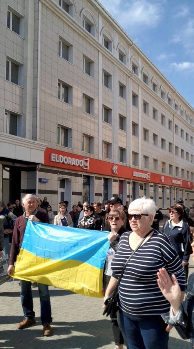 People hold Ukraine's national flag during a protest where tear gas was fired on them, amid Russia's invasion of Ukraine, in Kherson