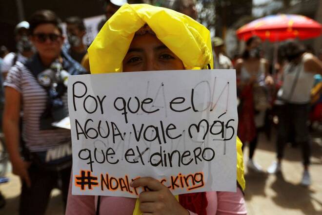 A woman holds a sign that reads: "Because water is worth more than money", during a protest against the use of fracking, in Bogota