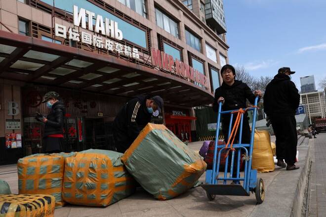 Men move bags of goods for export in front of a trading centre that houses shops and offices with Russian goods and services, in Beijing