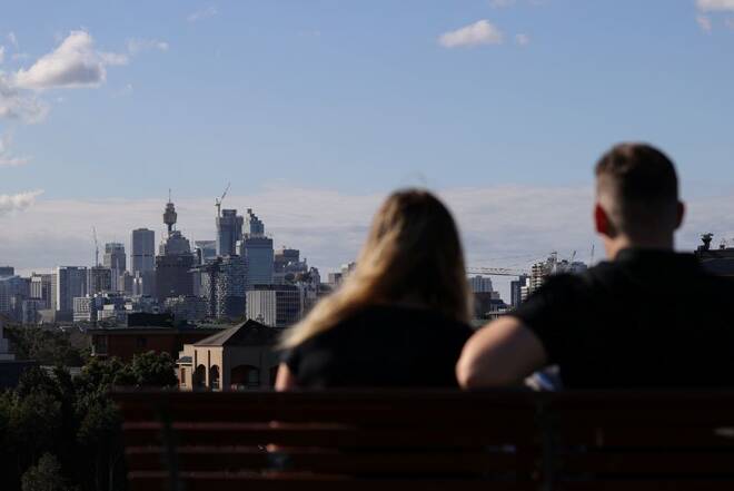 People sitting on a bench at Sydney Park gaze at the city centre skyline in Sydney