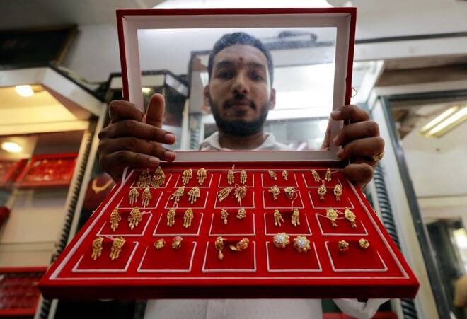 A vendor shows gold stud earrings at a jewellery showroom in Colombo