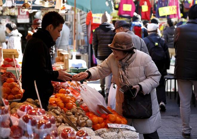 A woman pays money as she buys fruits outside a vegetable store at Ameyoko shopping district in Tokyo