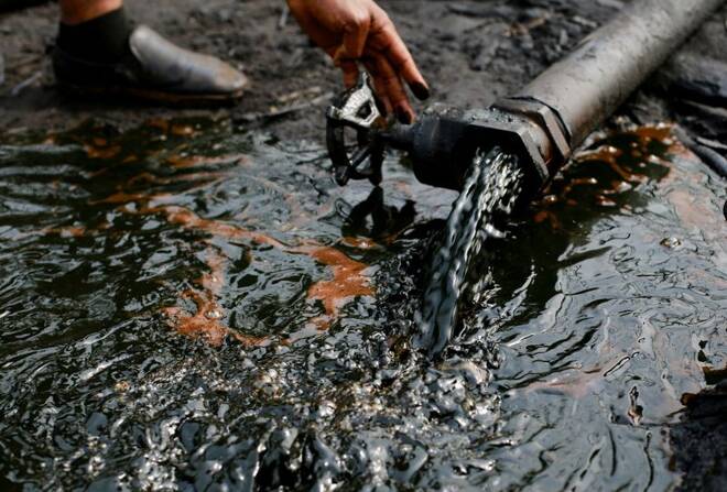 A person operates a tap of crude oil during the destruction of Bakana ii illegal camp in Okrika