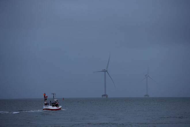 A fishing boat sails in front of wind turbines through the Thyboron Canal in Jutland, Denmark
