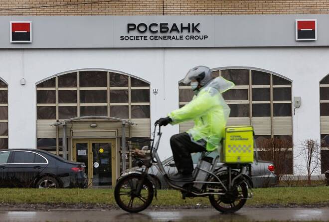 A food delivery courier rides past the Rosbank branch in Moscow