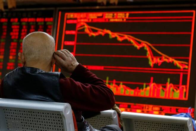 FILE PHOTO - An investor sits in front of a board showing stock information at a brokerage office in Beijing