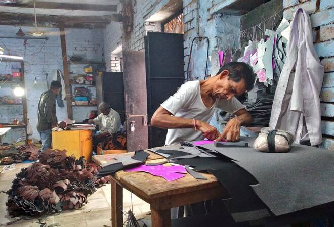 Ashok Kumar cuts synthetic leather to make shoes at a small shoe making factory in Agra