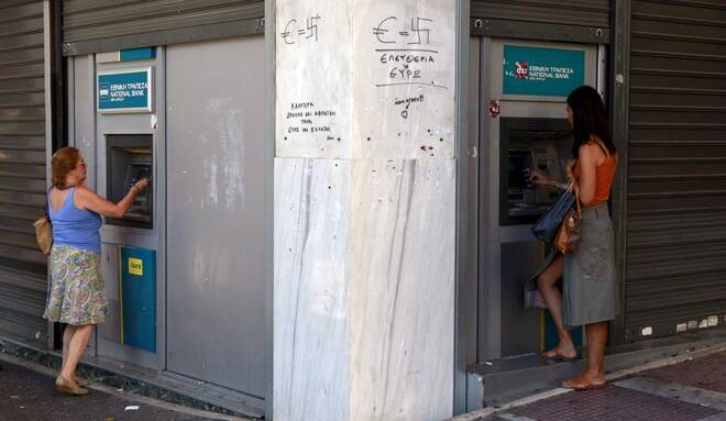 Women take money from separate ATM machines in central Athens, Greece