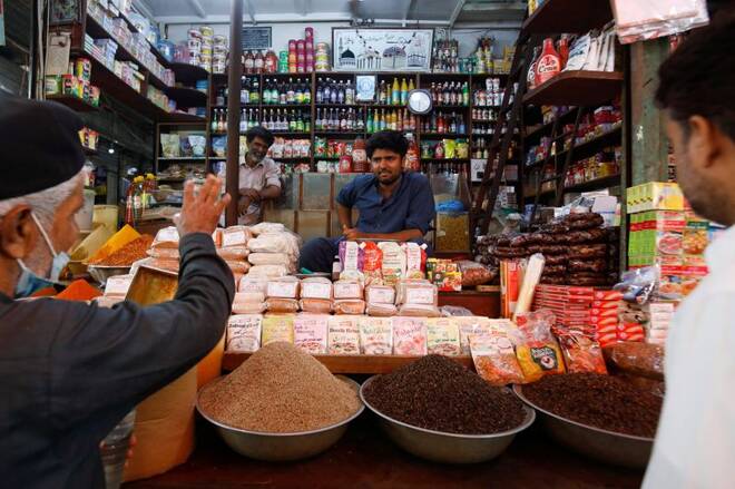 A shopkeeper listens to a customer as he sells groceries at a shop in a market, in Karachi