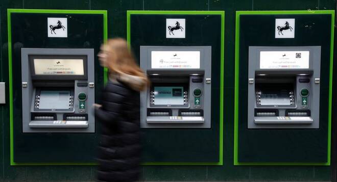 A woman walks past a row of cash machines outside a branch of Lloyds Bank in Manchester