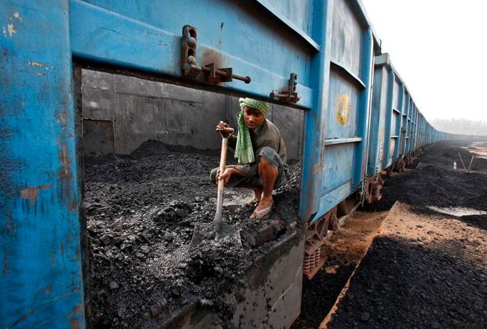 Trabajador descarga carbón de un tren de mercancías en un patio ferroviario en Chandigarh