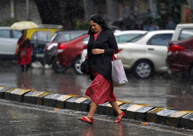 A woman crosses a road as it rains in Mumbai, India