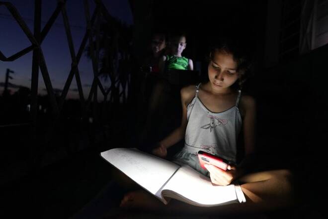 Emily Villega does her homework using the light of a cell phone during a blackout in Guanajay