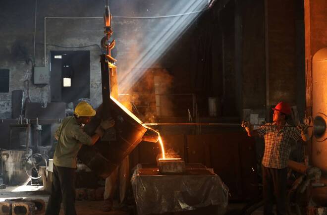 Workers pour molten iron into a mould at a workshop in Hangzhou, Jiangsu