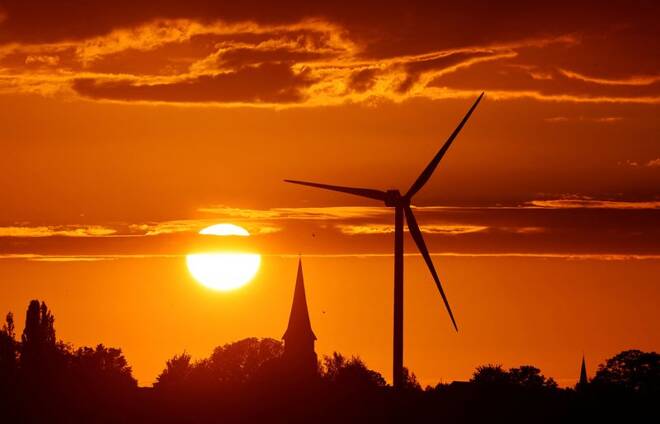 A power-generating windmill turbine and the church of the village are pictured during sunset at a wind park in Ecoust-Saint-Mein