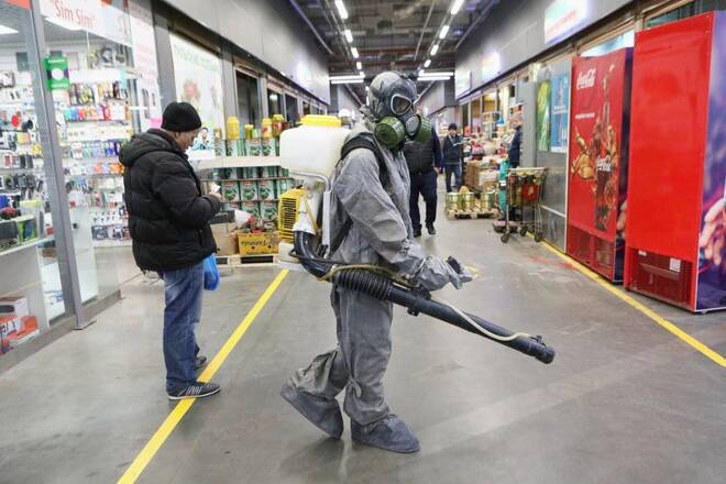 A specialist wearing protective gear sprays disinfectant inside the market in Moscow