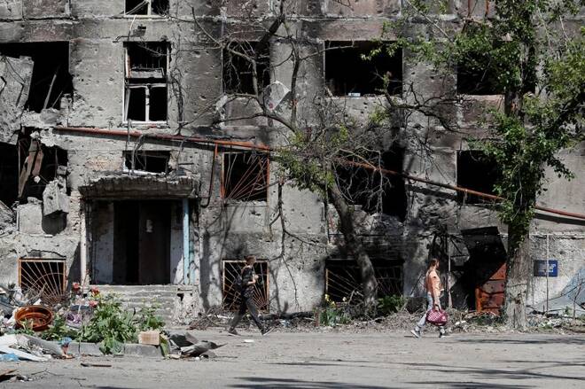 People walk past a heavily damaged residential building in Mariupol