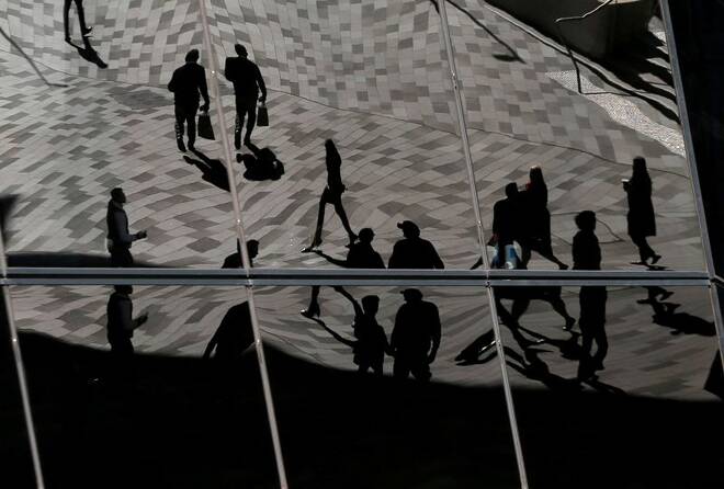 Workers are reflected in an office building's windows in Sydney's Barangaroo business district in Australia's largest city