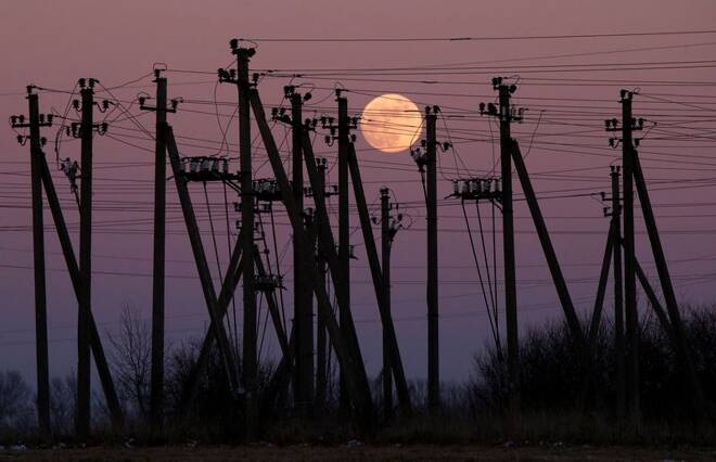 A full moon is seen rising through electric poles near Virbalis