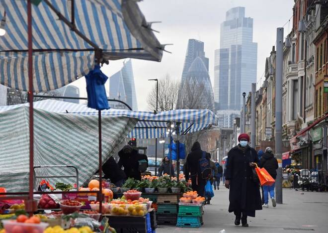 People shop at market stalls, with skyscrapers of the CIty of London financial district seen behind, in London
