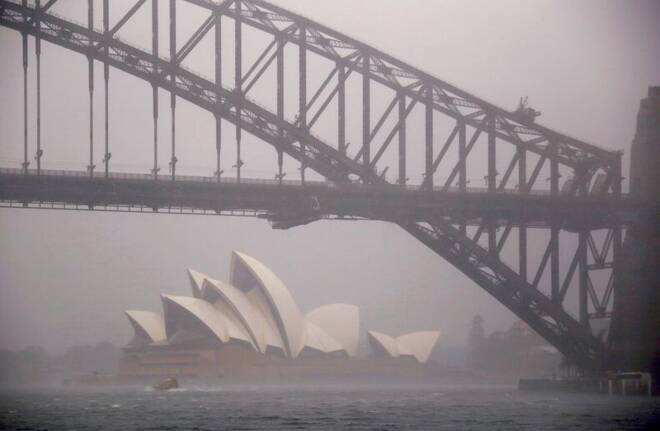 A boat passes under the Sydney Harbour Bridge and in front of the Sydney Opera House as strong winds and heavy rain hit the city of Sydney
