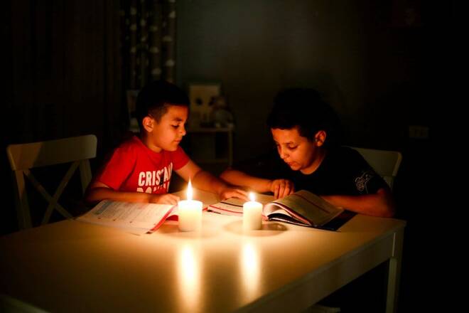 Children study by candlelight during a power outage, at home in Tripoli