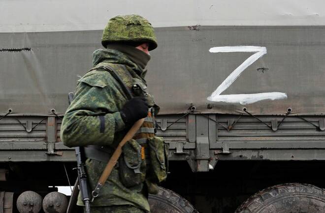 A serviceman of pro-Russian militia walks next to a military convoy in the Luhansk region