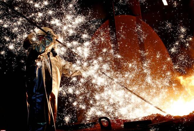 A steel worker of Germany's industrial conglomerate ThyssenKrupp AG stands a mid of emitting sparks of raw iron from a blast furnace at Germany's largest steel factory in Duisburg