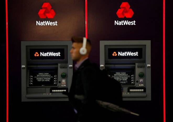 A man walks past ATM machines at branch of the NatWest bank in Manchester