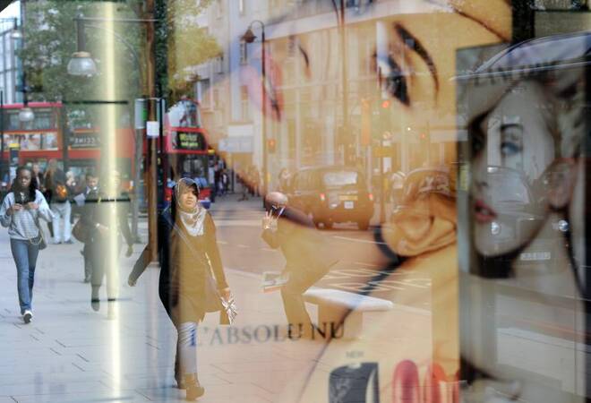 Pedestrians are reflected in a shop window as they walk along Oxford Street in central London