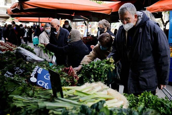 Customers buy vegetables at a farmers market in Athens