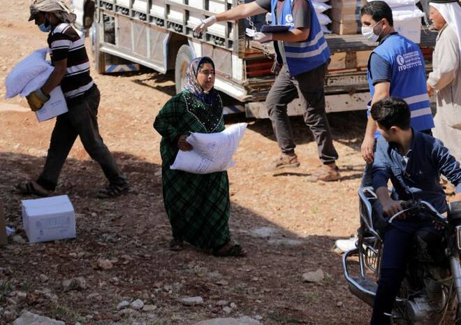 An internally displaced Syrian woman walks as she holds a bag of humanitarian aid in the opposition-held Idlib