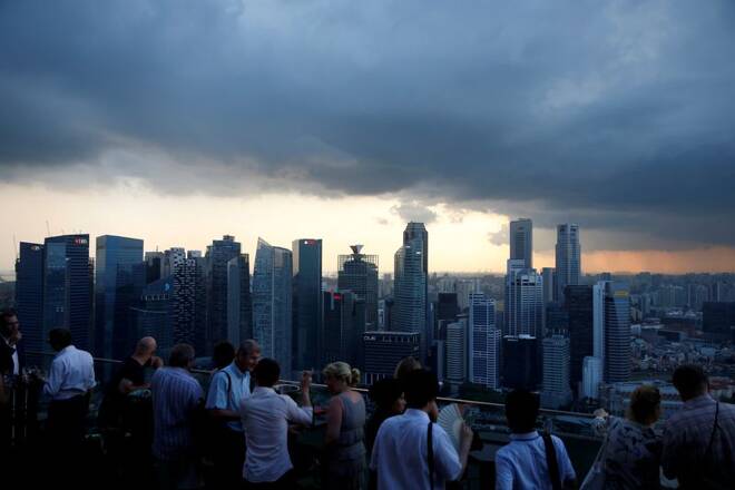Tourists have drinks at a hotel rooftop bar as clouds gather over the central business district in Singapore
