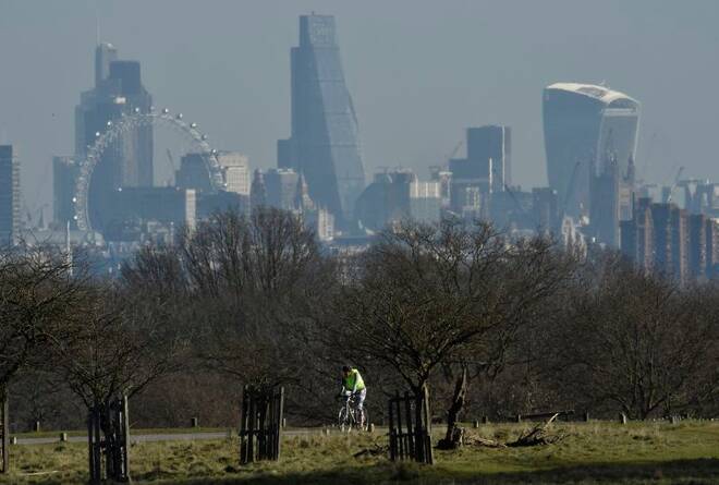 A cyclist rides through Richmond Park, with the City of London financial district seen behind in London