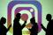 Silhouettes of mobile users are seen next to a screen projection of Instagram logo in this picture illustration