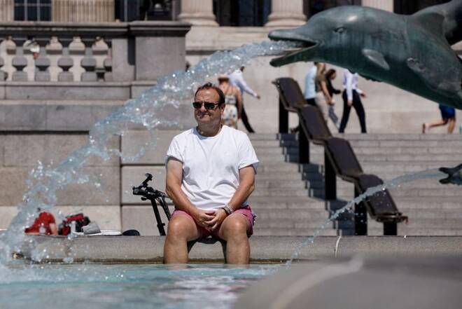 A man cools off in a fountain during the hot weather in London, Britain