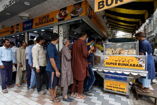 People wait for their turn to buy low-priced bun-kabab from a shop in Karachi