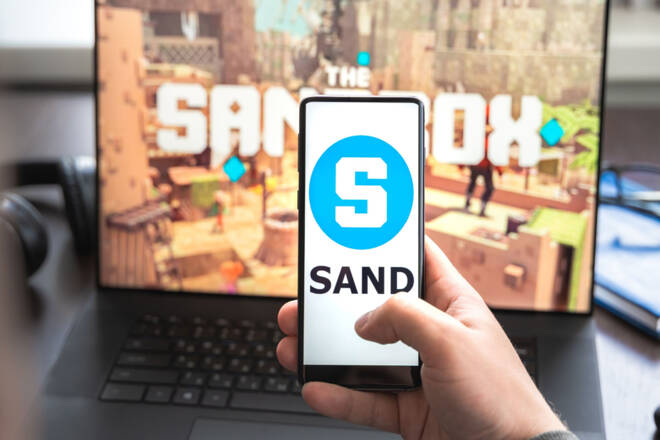 The Sandbox logo on a phone alongside laptop