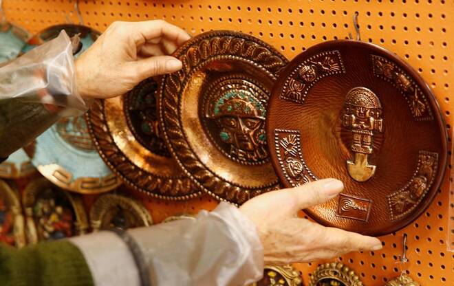 A vendor shows copper plates displayed for sale at a handicraft shop in Lima