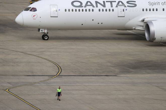 A ground worker walking near a Qantas plane is seen from the international terminal at Sydney Airport in Sydney