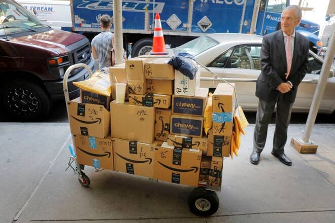 A delivery cart loaded with a number of packages from Amazon stands on a sidewalk in New York City