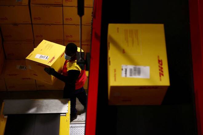 An employee carries a DHL delivery package inside the new DHL Express hub near Paris