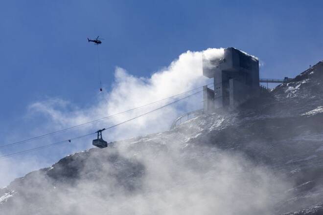 An helicopter carries water to stop an ongoing fire at the restaurant Botta at the Glacier 3000 in Les Diablerets