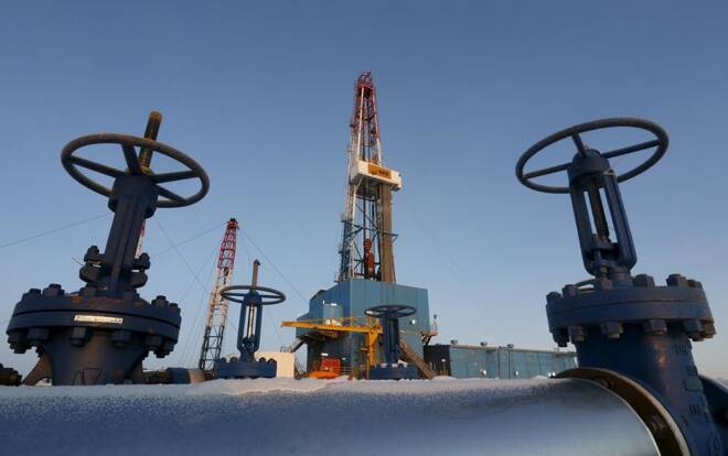 An oil pipe is seen in front of a drilling rig at a Lukoil-owned oil field outside the West Siberian city of Kogalym