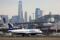 A JetBlue passenger jet lands with New York City as a backdrop